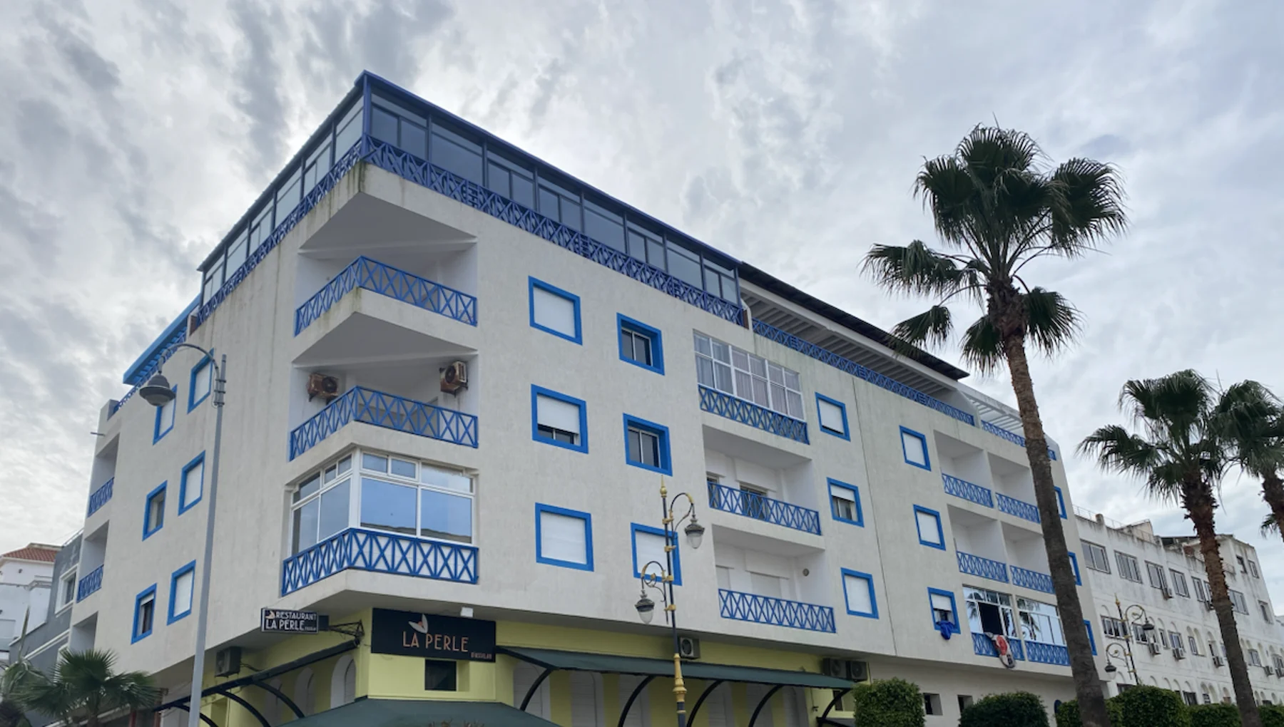Photographie de 2026 montrant la façade blanche et bleue de La Perle d’Asilah après sa rénovation